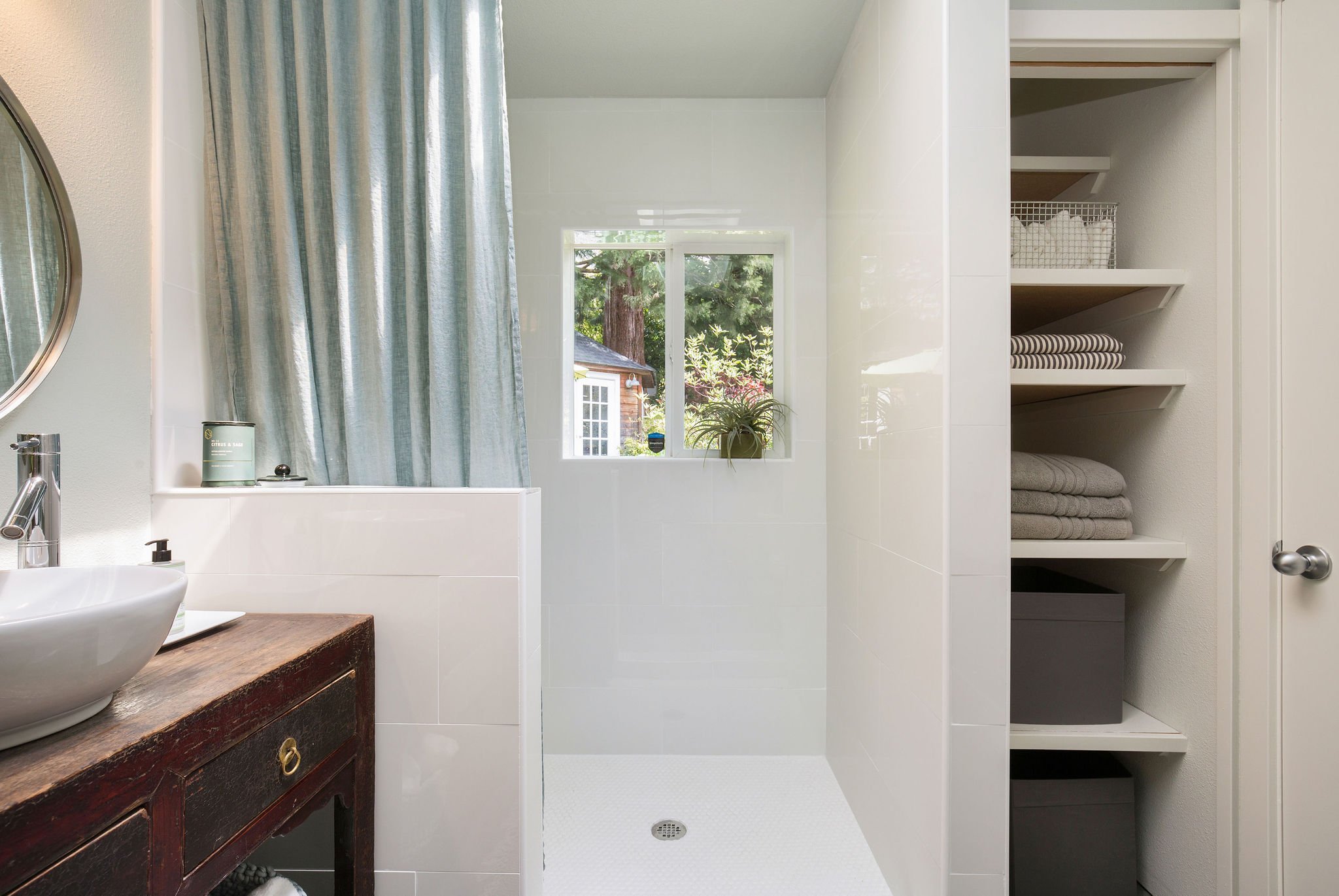  image description: interior of bathroom with standing shower and shelves 