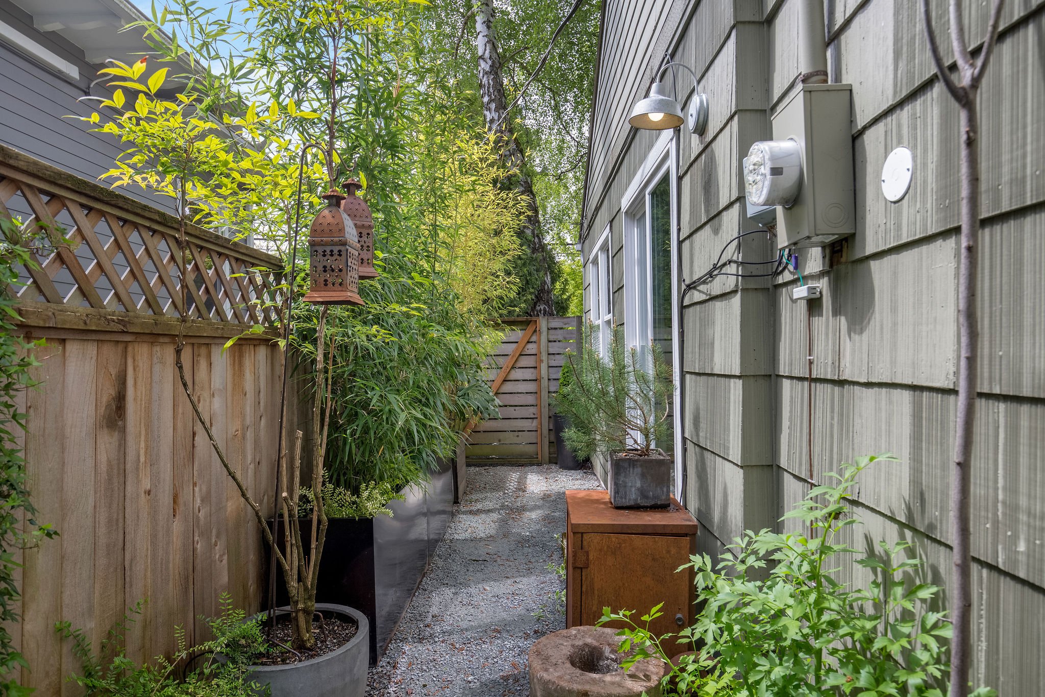  image description: exterior of green one story cottage with garden and yard with view of side pathway 