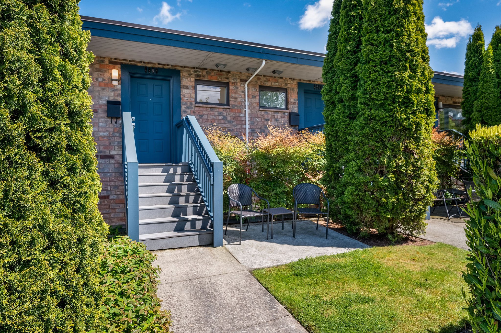  Image description: exterior of condo with stairs and small garden 