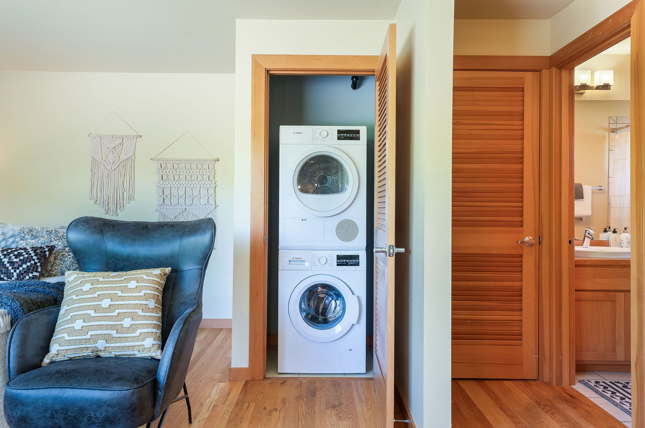  Image description: interior of studio with couch, armchair, queen bed, and view of closet with washer and dryer 