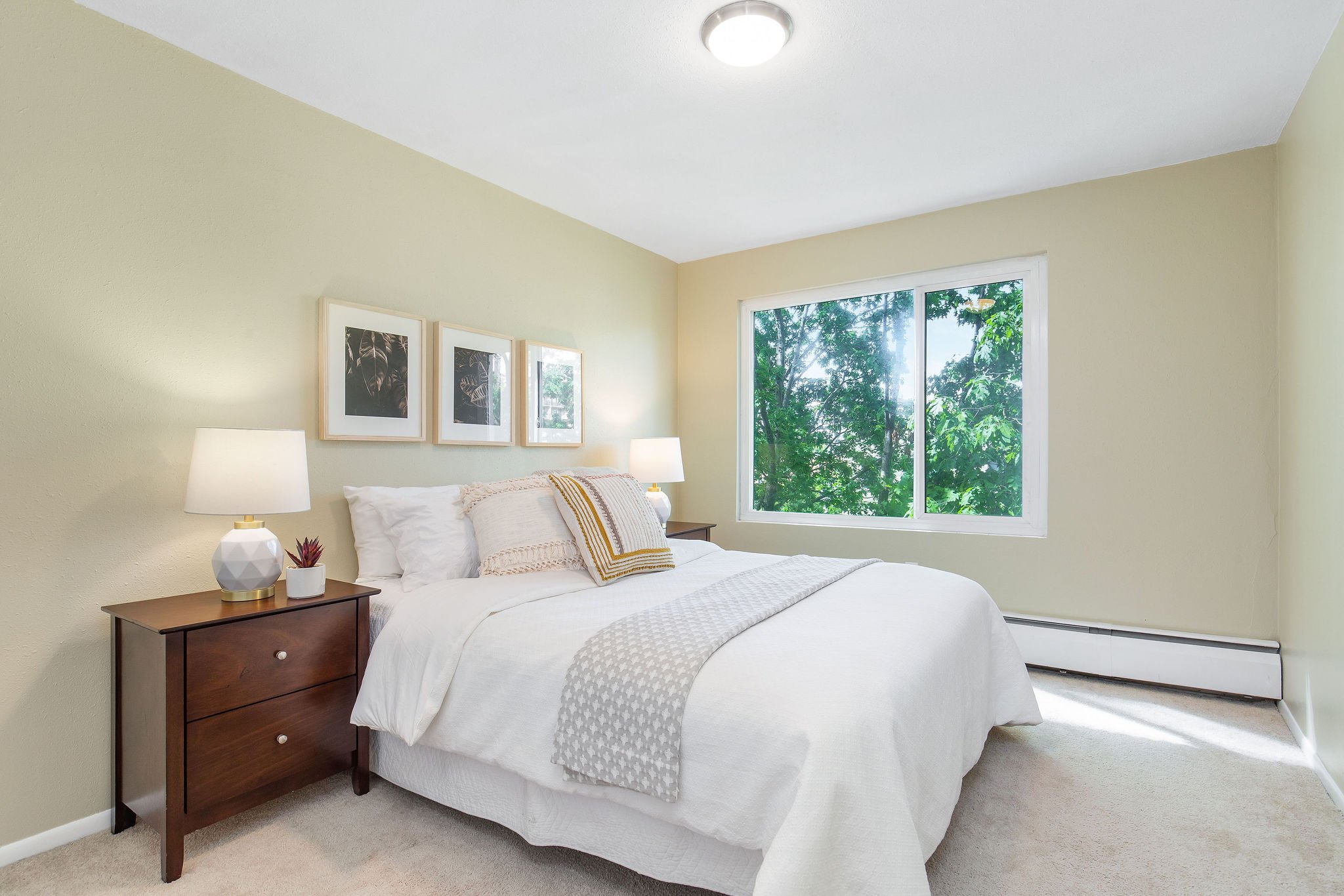  image description: interior of bedroom with queen bed, window, and tan carpet 