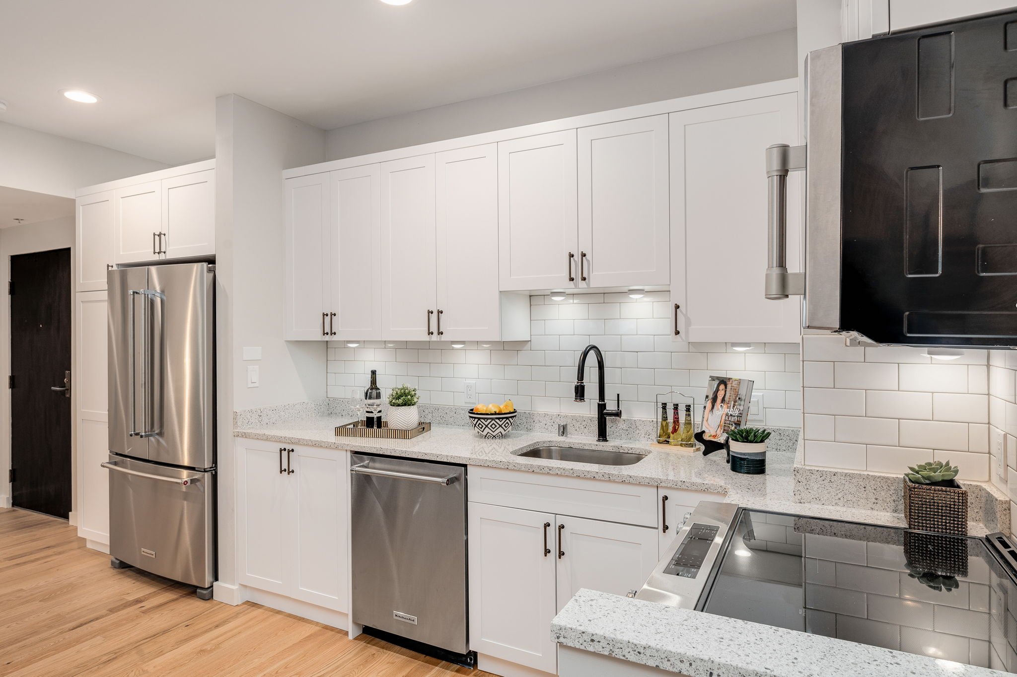  view of white kitchen with quartz countertops, hardwood floors, and cabinet space 