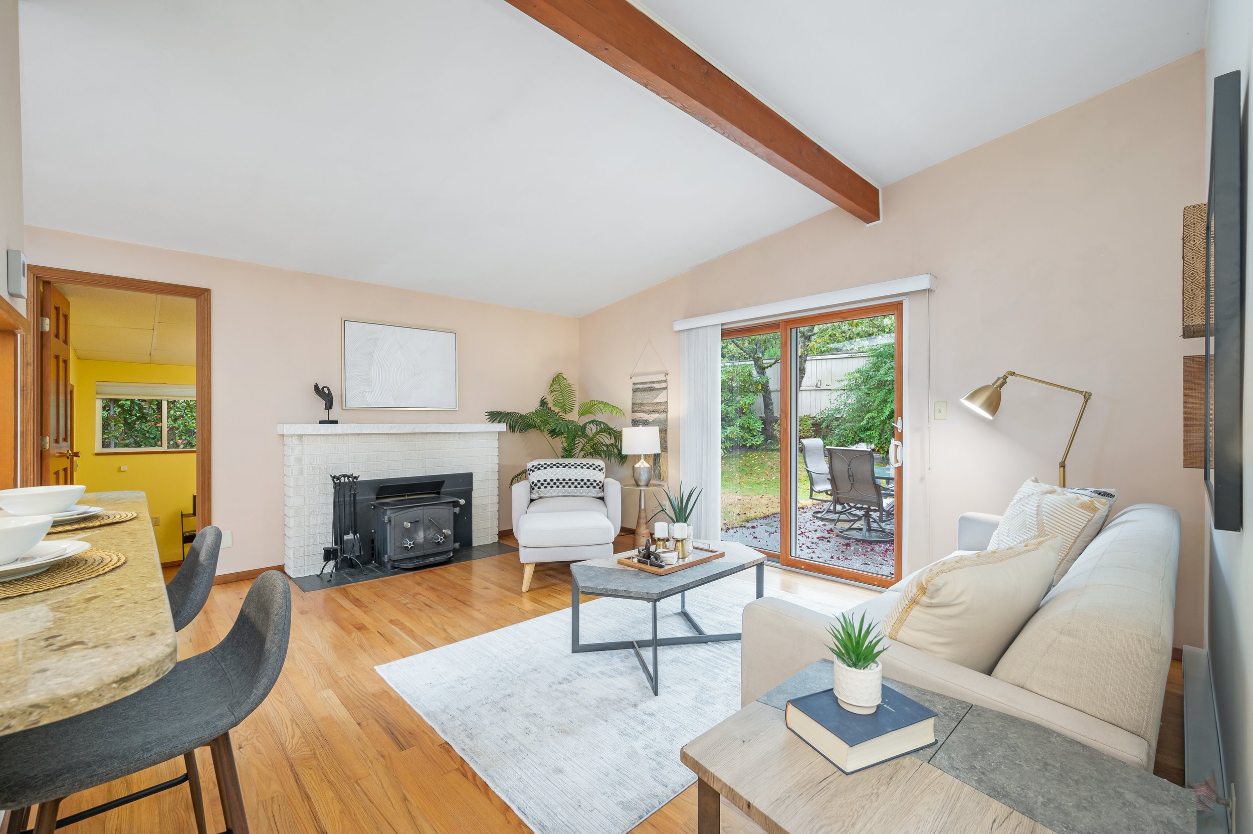  interior of living room with hardwood floors, sliding glass door, fireplace, couch and chairs 