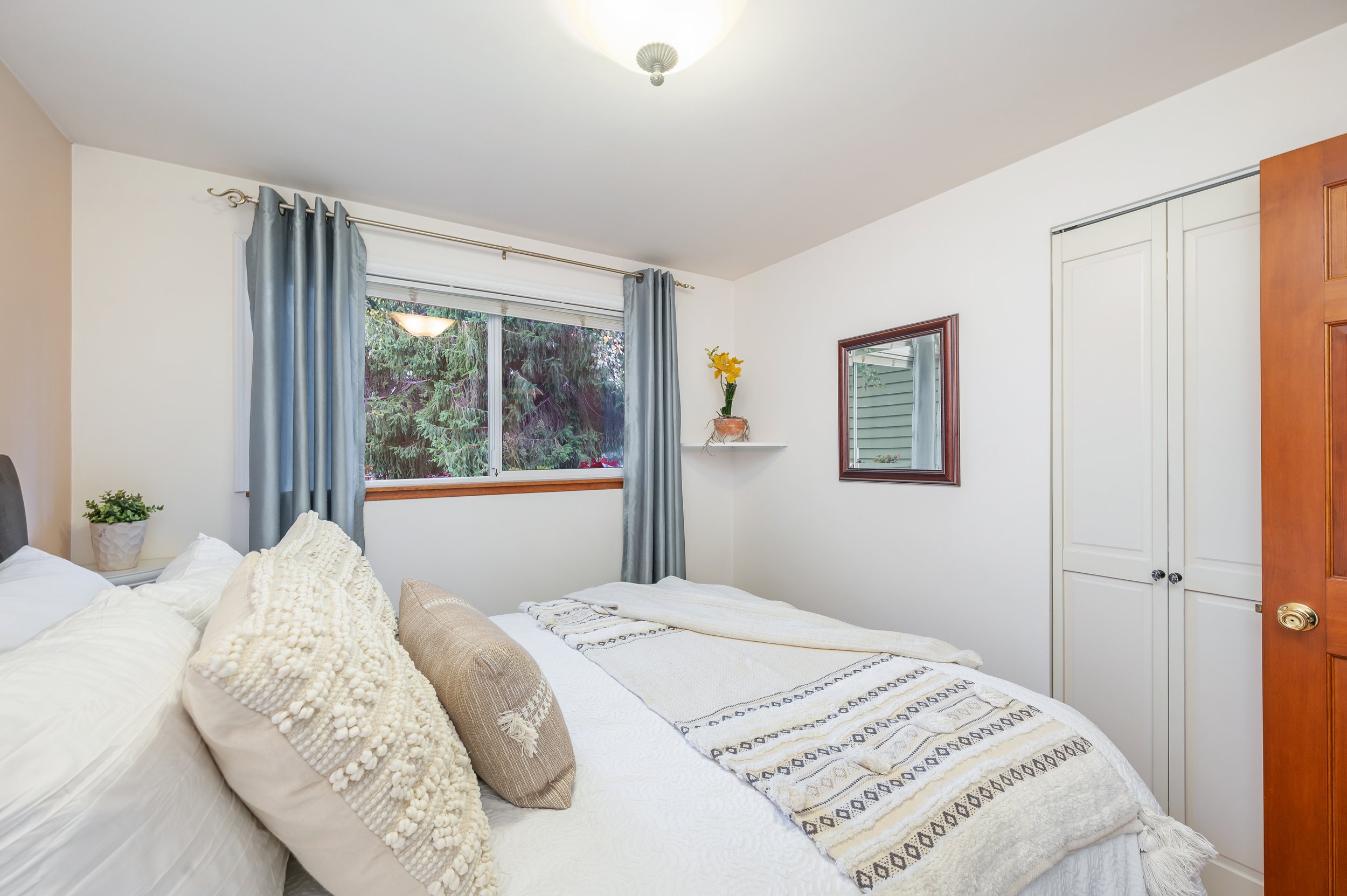  interior of bedroom with large window, carpet, closet, and queen bed 