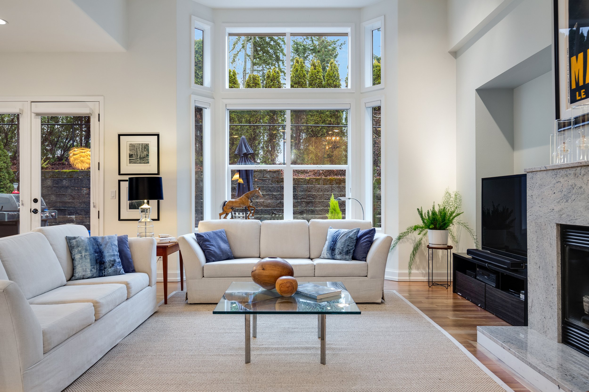  interior of living room with rug, large windows, fireplace, french doors, and couches 