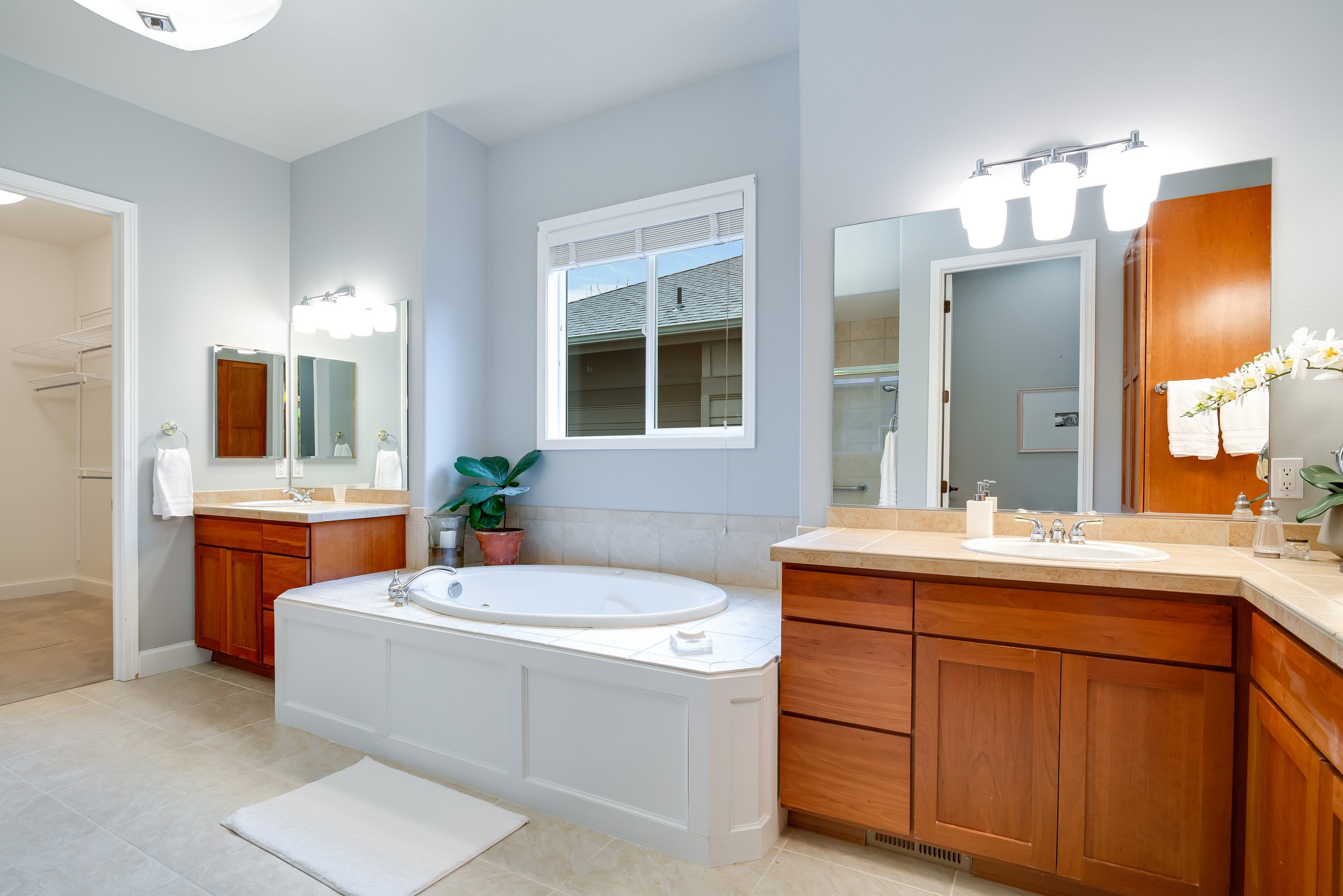 interior of master bathroom with large bathtub and walk in shower, window, and two sinks 