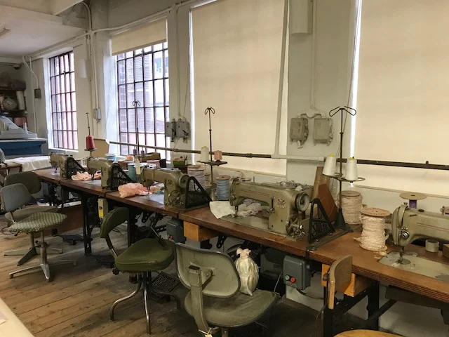 A row of sewing machines where seamstresses sat for 12 hours a day making coffin shrouds. 