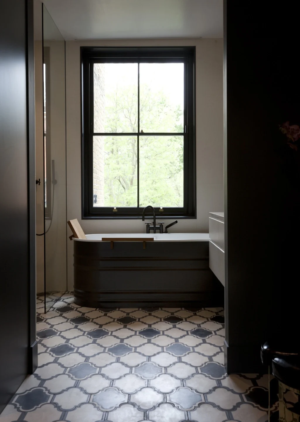 On the floor of the main bathroom, the Lantern model from Popham Design echoes the large black window frame and the black fittings.