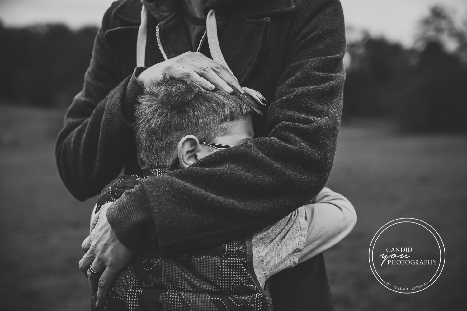 Dad hugs son with love and son nestles head in dad's body black and white photography