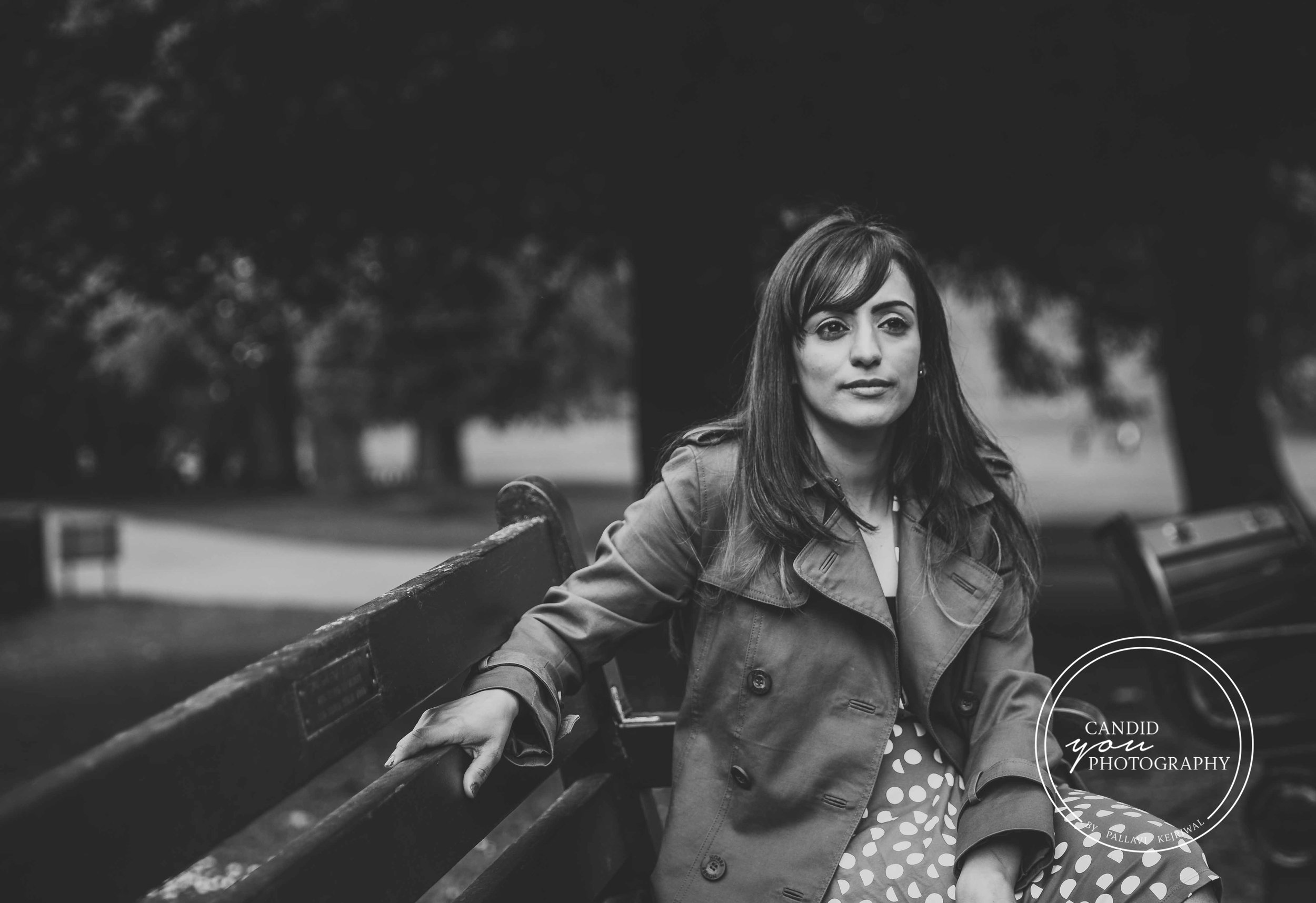 Beautiful lady sitting on park bench in burberry jacket