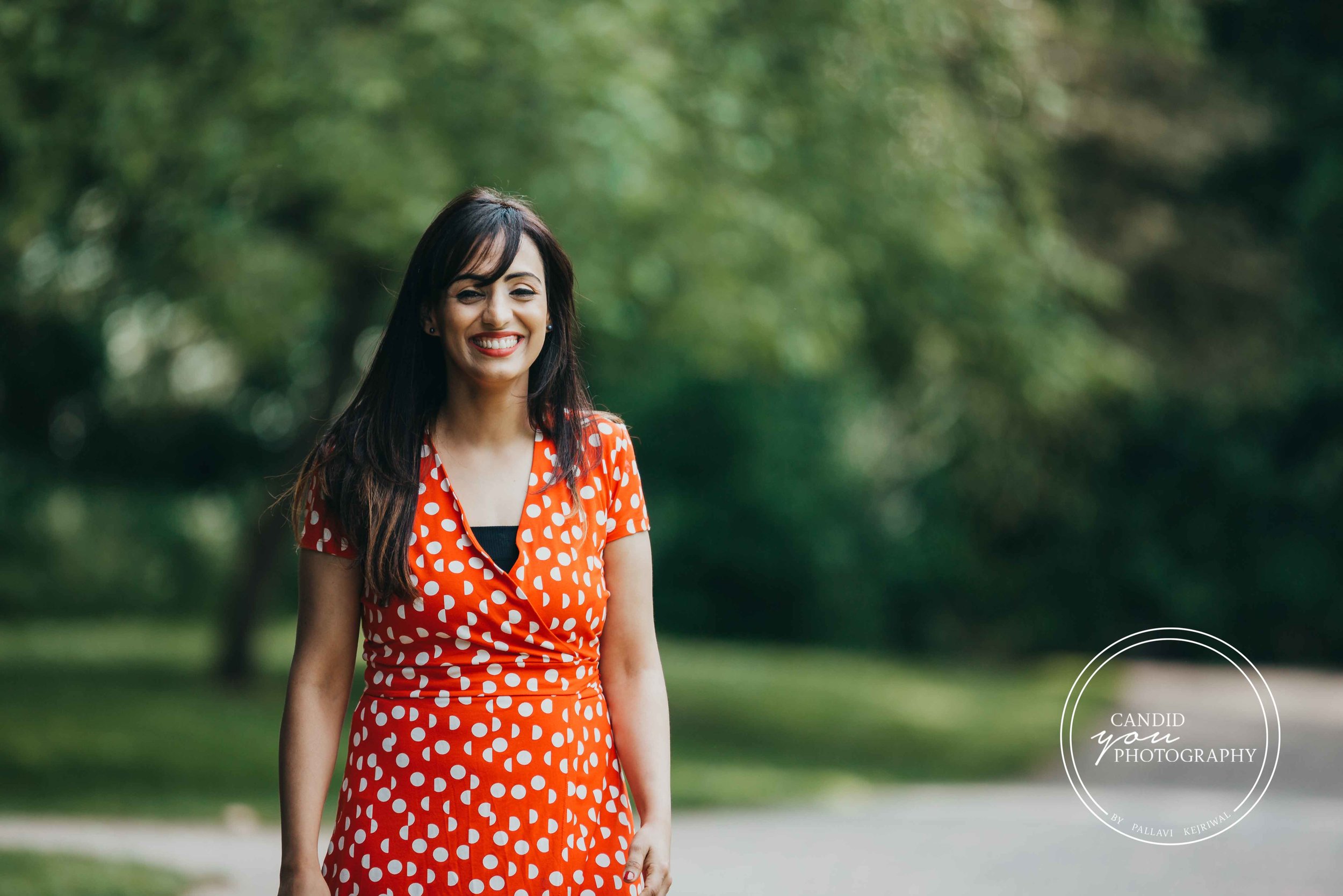 Beautiful lady smiling in orange polka dot dress in park