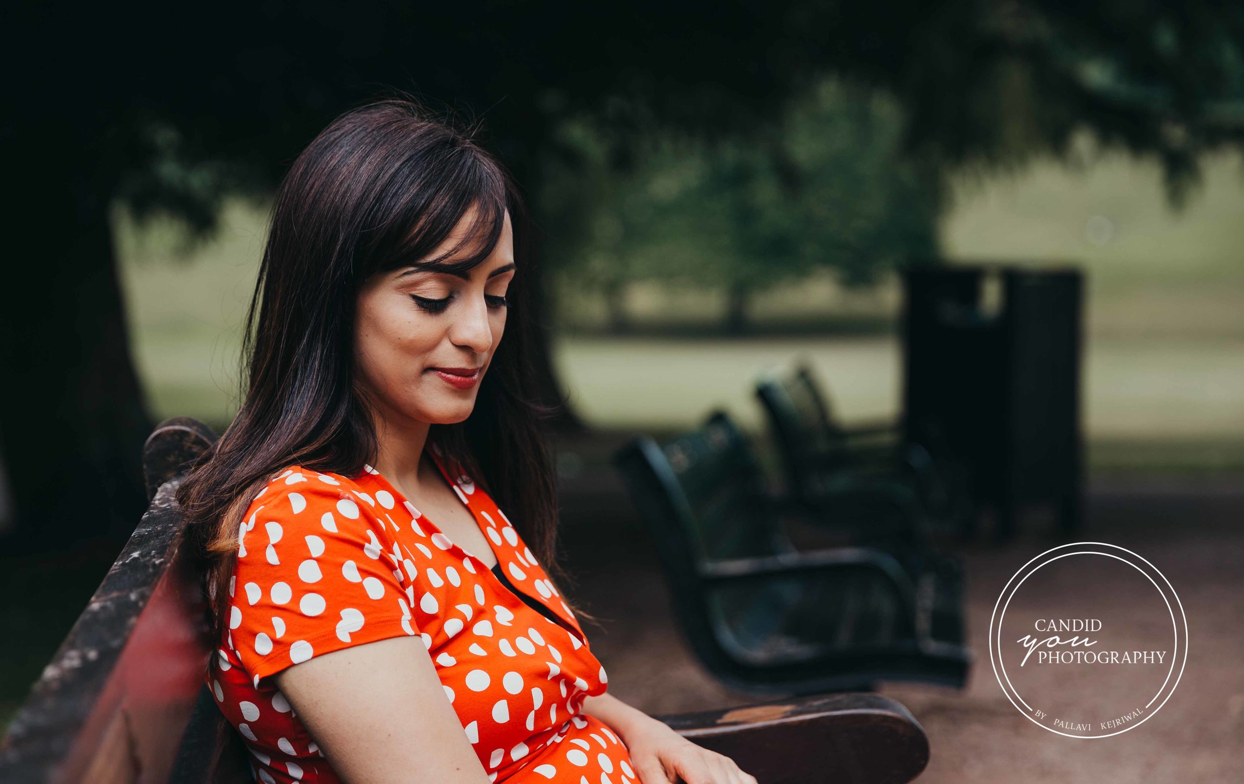 Beautiful lady sitting on the park bench in orange polka dot dress