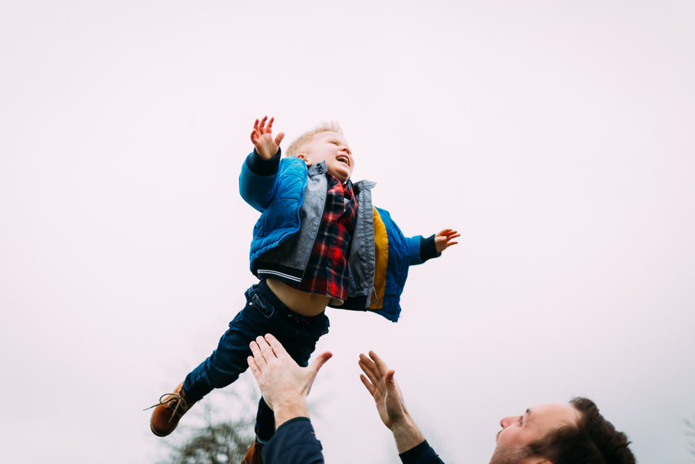 Father happily flinging his child in air and son laughing happily