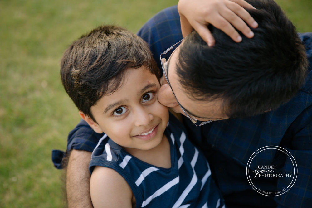 son looks on while dad kisses him