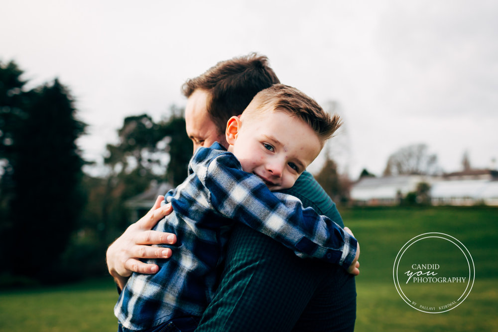 boy lovingly looks towards camera while being hugged by dad