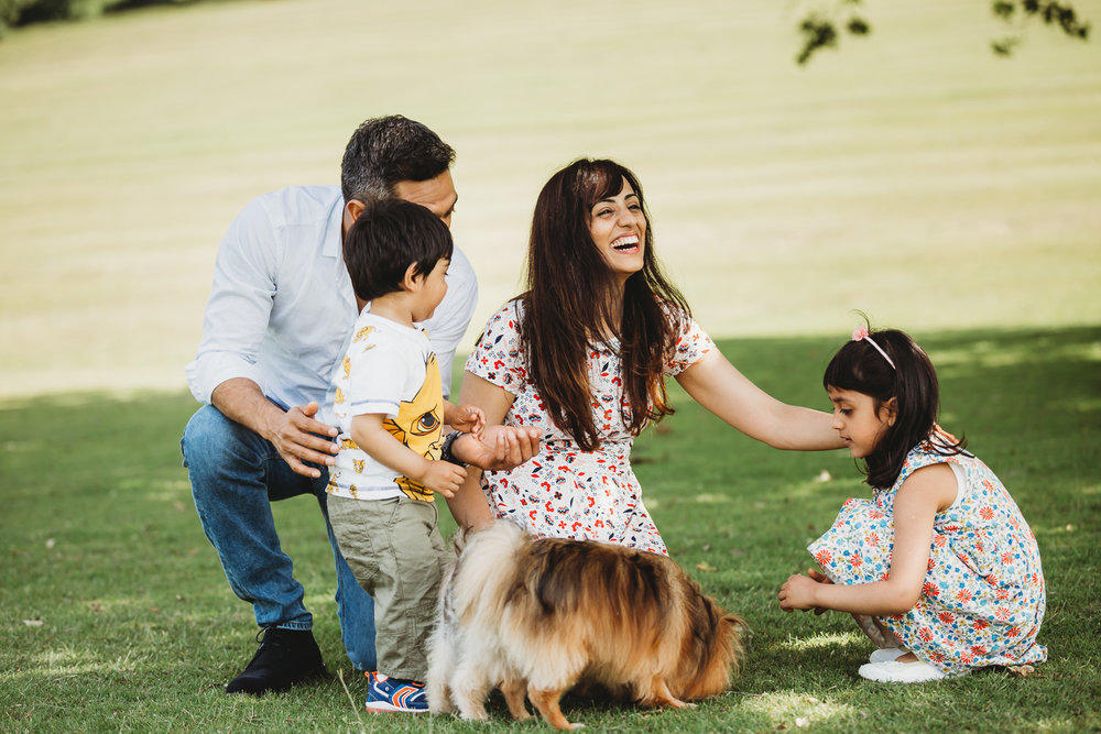 Family of four smiling in the park with dog