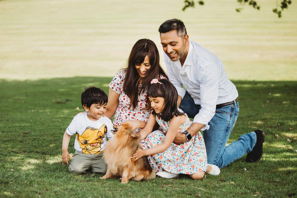 family of four enjoying with dog in park