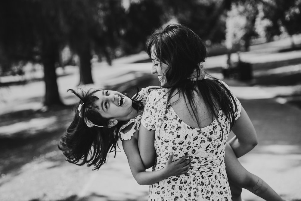 daughter laughing while mum twirls her around in a circle