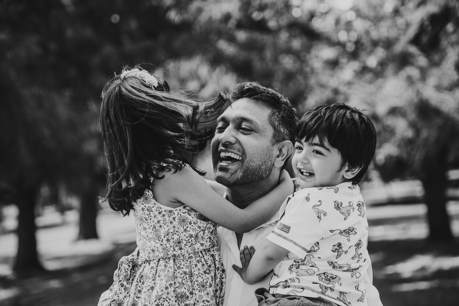 father laughs with and hugs his two children - one boy one girl