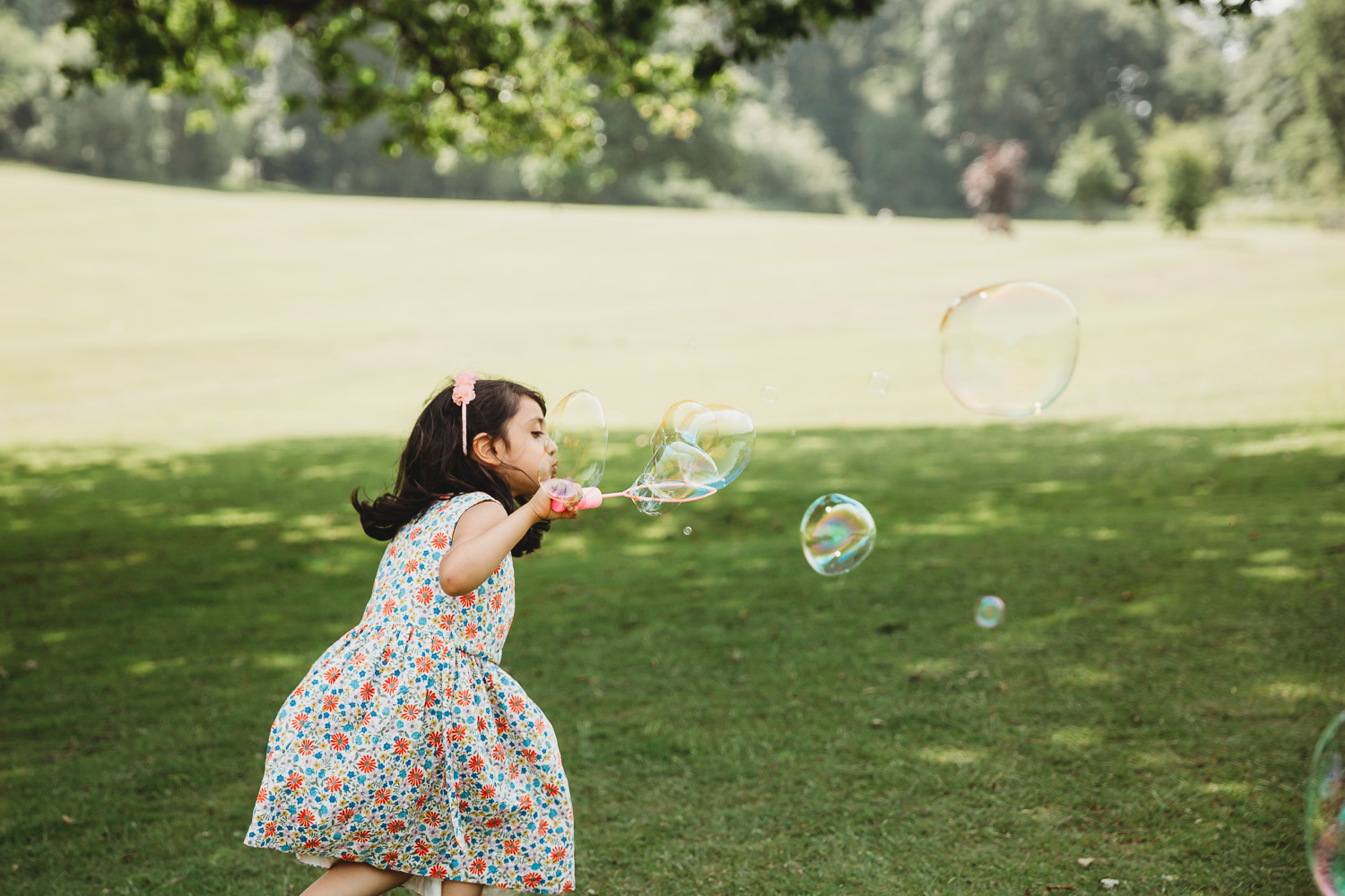 Girl of four blows bubbles in the park