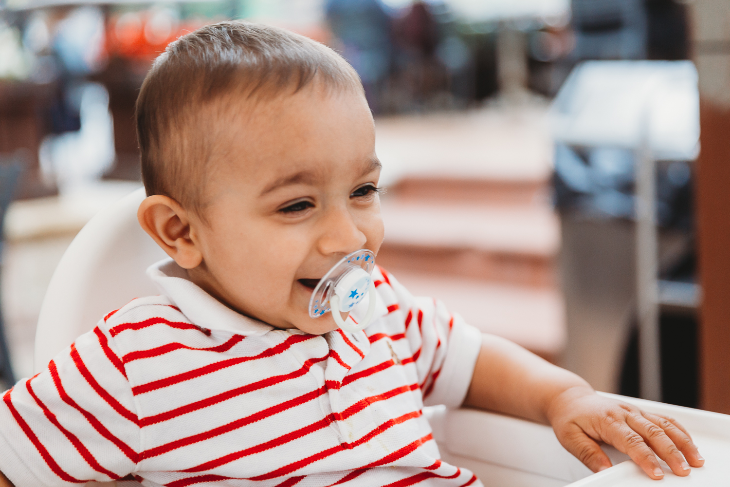 boy laughing with pacifier in his mouth