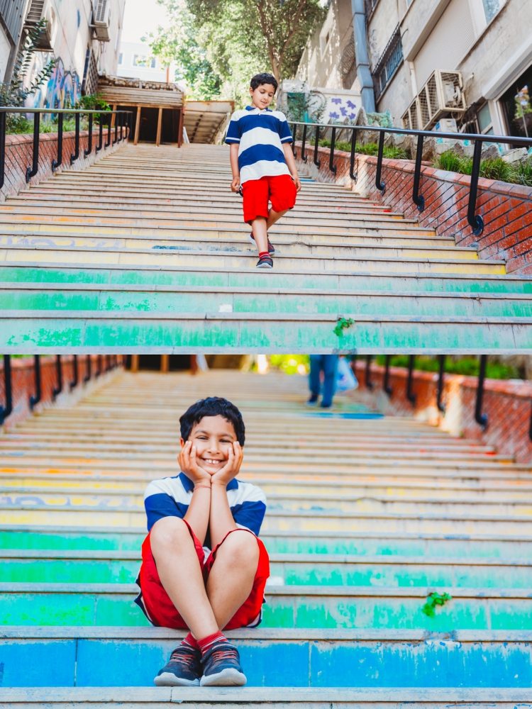 7 year old boy sitting on colourful steps and smiling