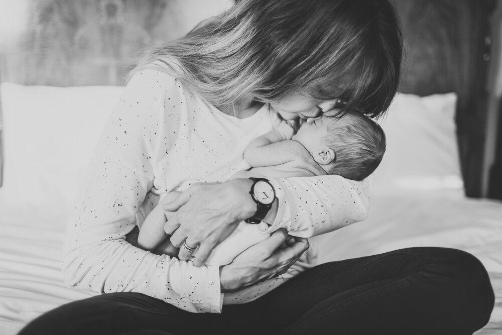 Mum kissing newborn baby at home in b15