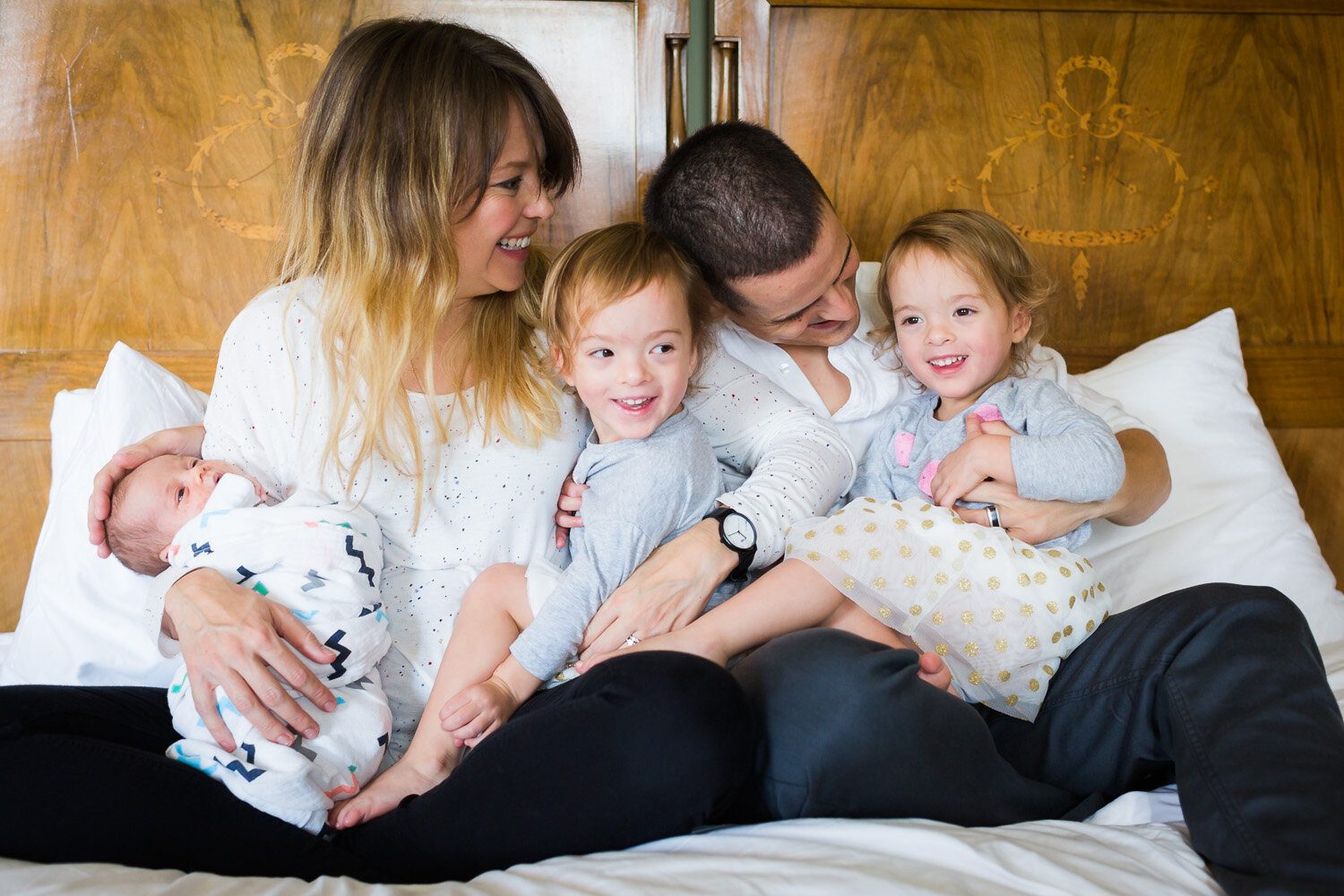 family laughing on the bed with newborn in birmingham