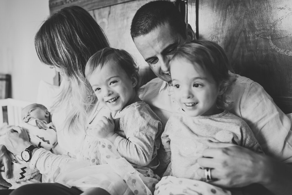 family cuddling and laughing with newborn on the bed in birmingham