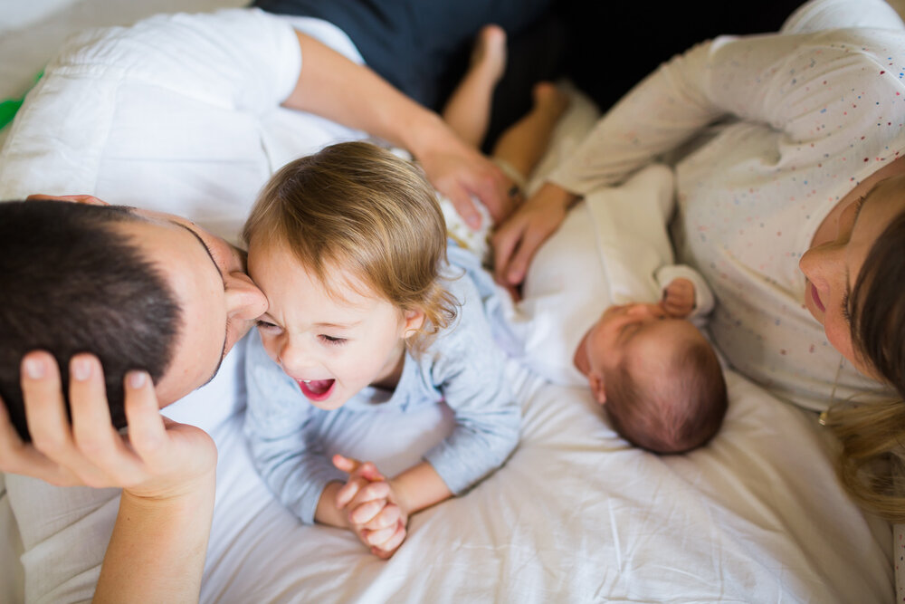 Family enjoying on the bed with newborn baby in birmingham