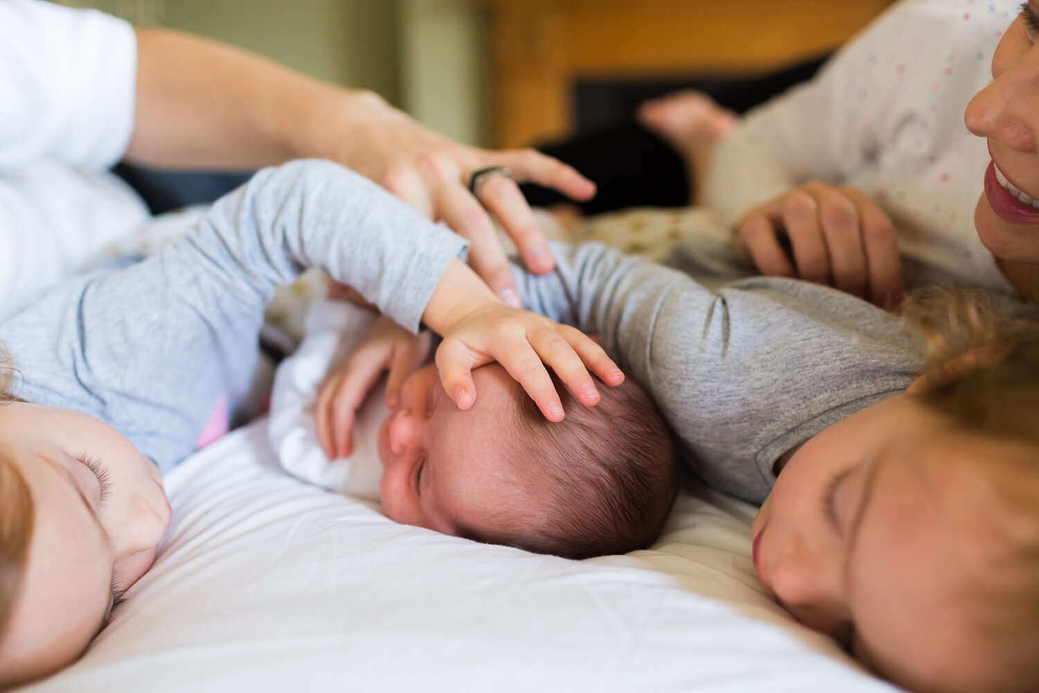 Family enjoying on the bed with newborn baby in birmingham