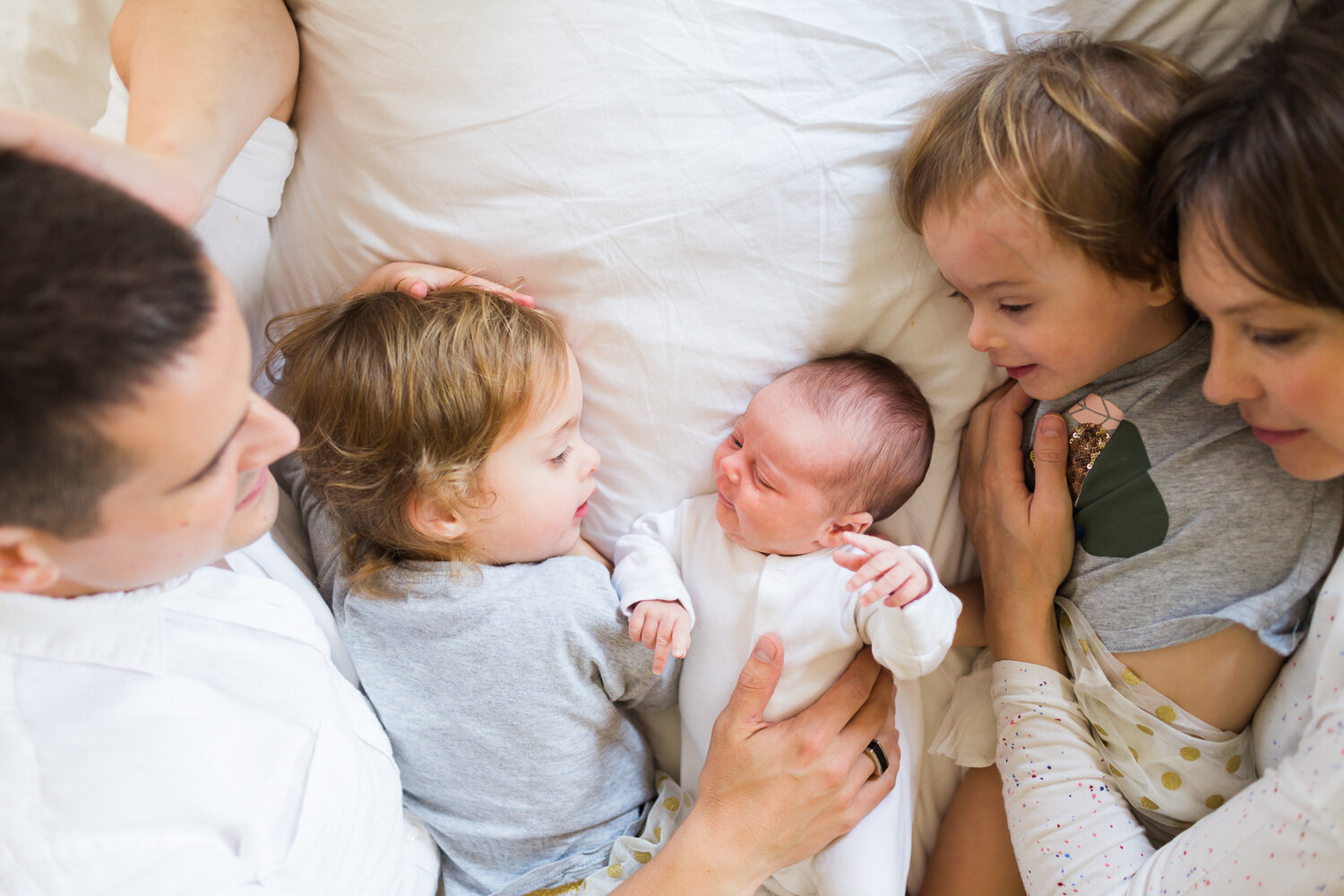 Family enjoying on the bed with newborn baby in birmingham