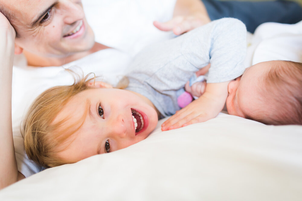 Family enjoying on the bed with newborn baby in birmingham