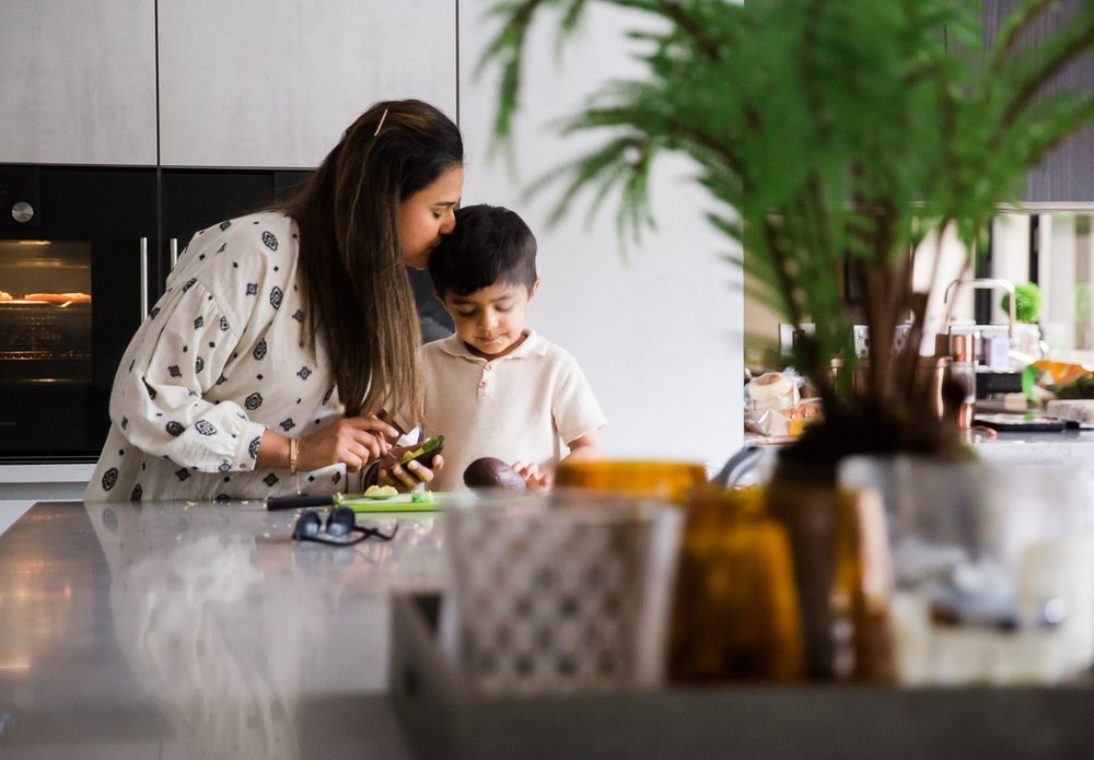 In-Home Family Photo Session In Wimbledon with Mum lovingly kissing son while making dinner