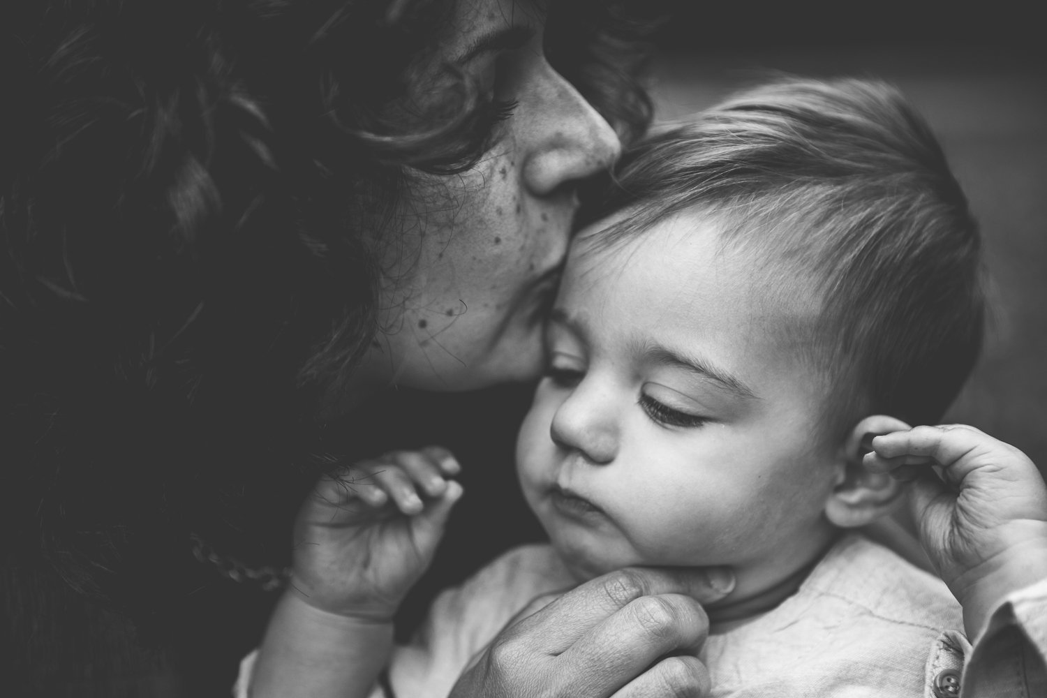 Mum tenderly kisses one year old toddler in outdoor family photoshoot in wimbledon