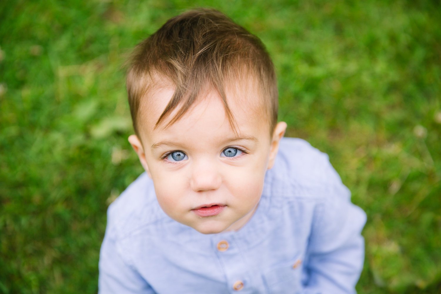 one year old toddler looks up at the camera in outdoor family photoshoot in wimbledon