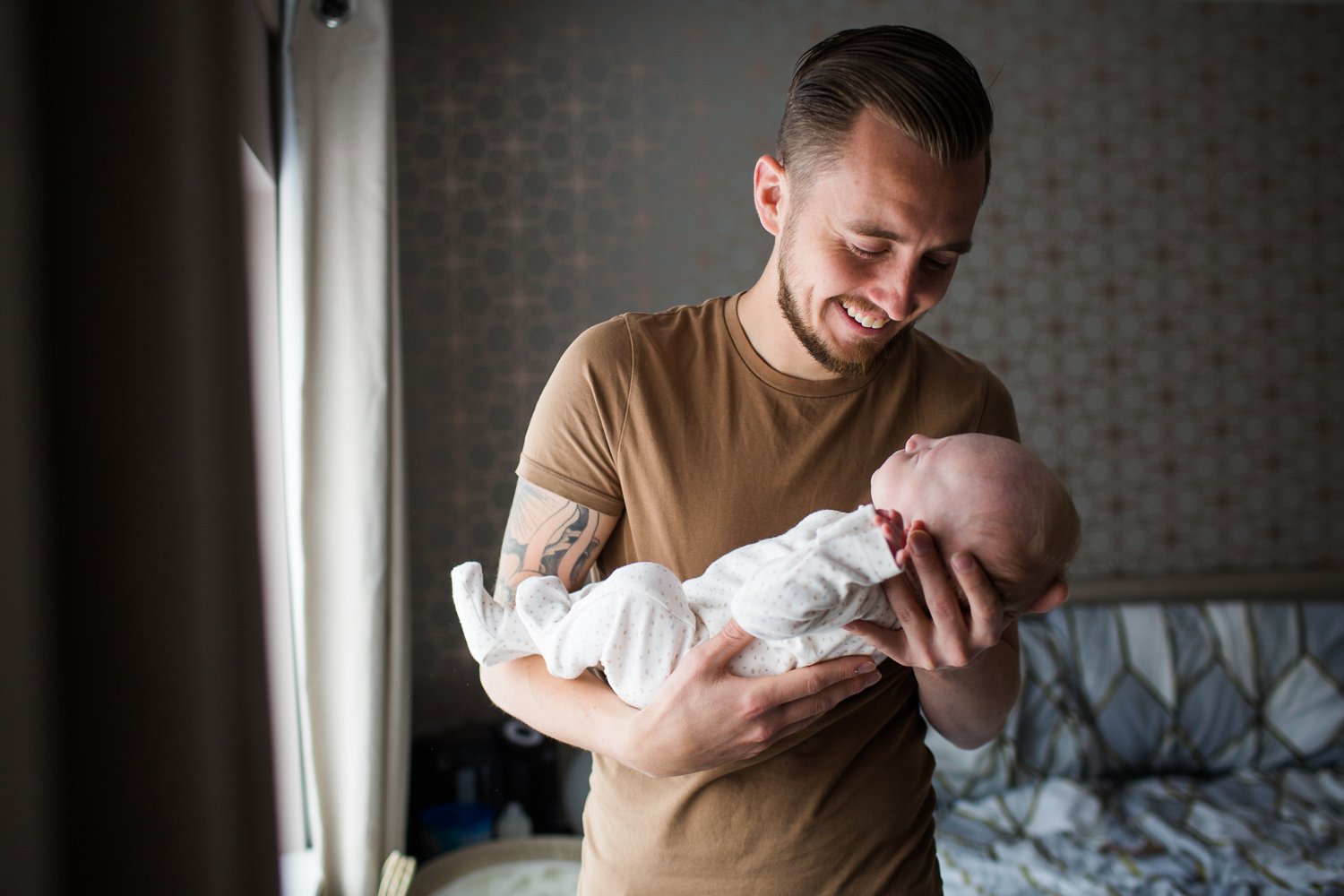 Wimbledon Newborn Photographer captures Dad looking lovingly at newborn son and laughing