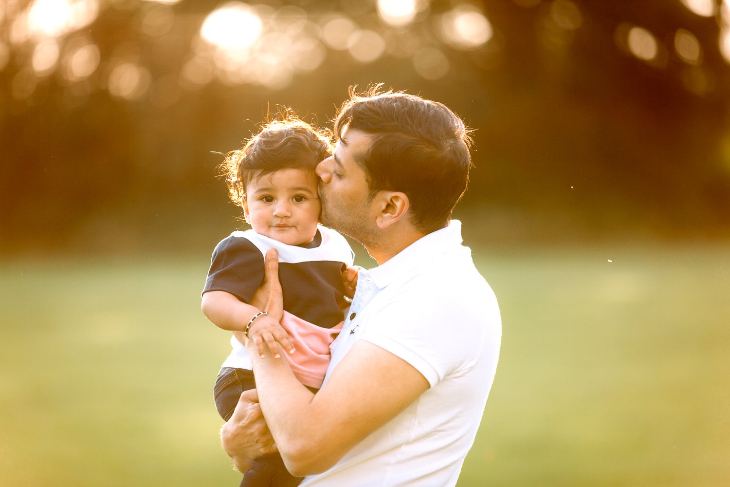 Wimbledon Family Photographer captures Dad kissing 6 month old baby in a park