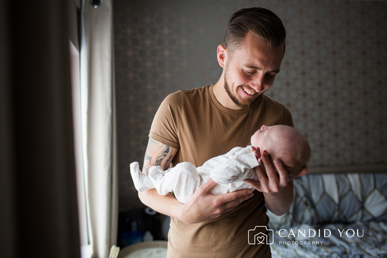 dad holding and smiling at newborn in kingston