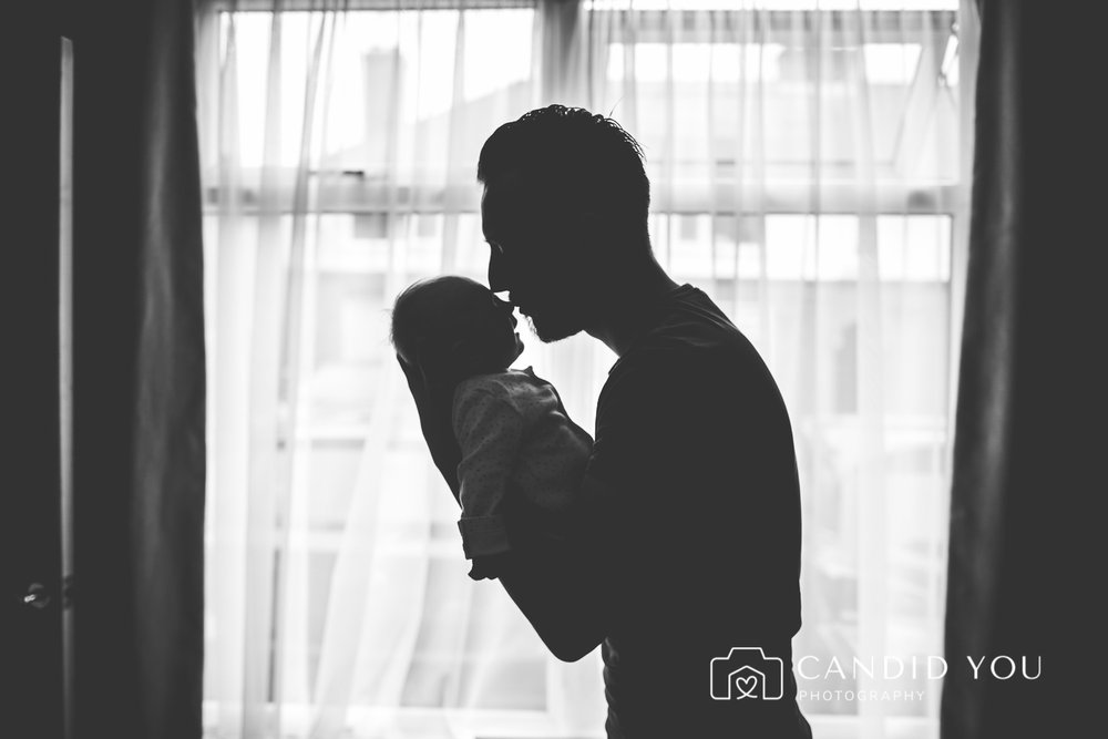 silhouette of father kissing newborn in putney