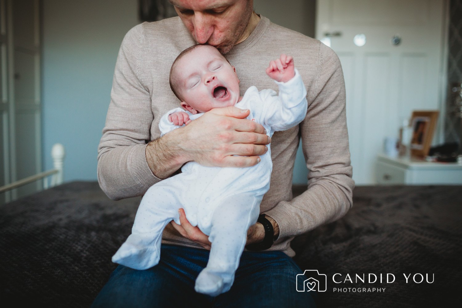 father holding newborn while she yawns in fulham