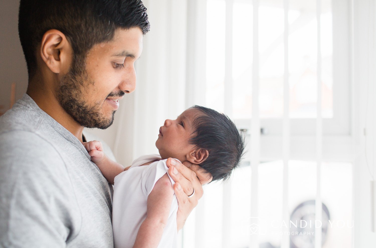 dad lovingly looks at newborn in putney