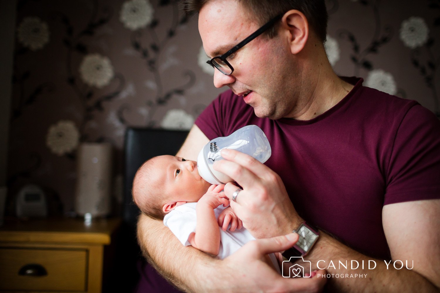 father feeding newborn with a bottle in wimbledon