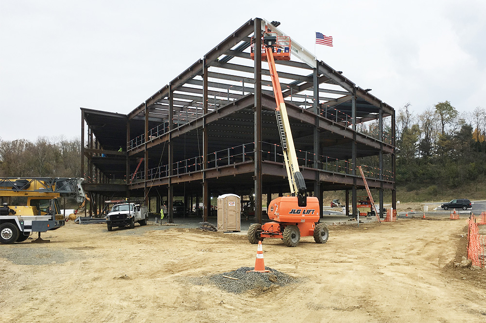 Following the ceremonial hoisting of the signed beam, the steel workers bolt the final beam into place.
