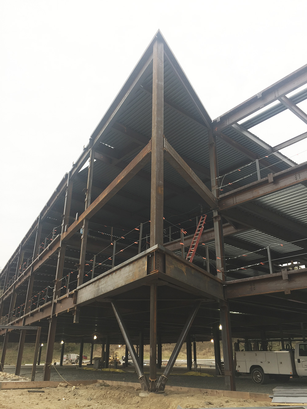 The building’s main entry is signified by a protruding two-story angle supported by a tripod column. While the building’s facade is mostly precast concrete, this portion of the building will feature a glass curtain wall.