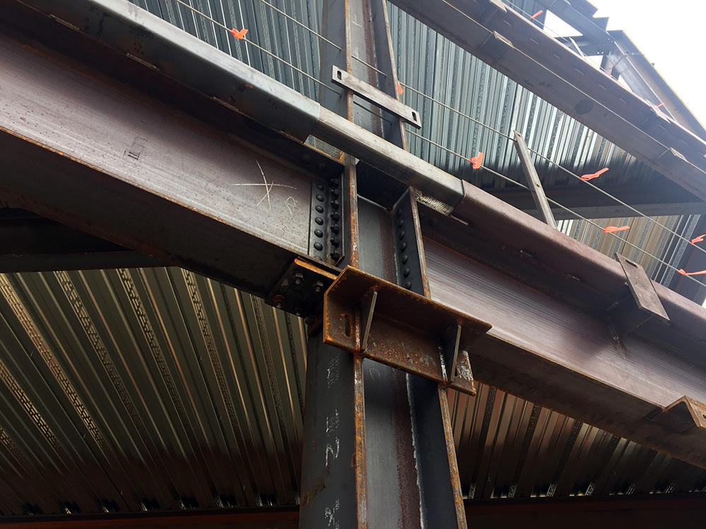 A close-up of a typical column/beam connection. The brackets welded to the front of the columns are positioned to hold precast concrete panels currently waiting to be lifted onto the building.