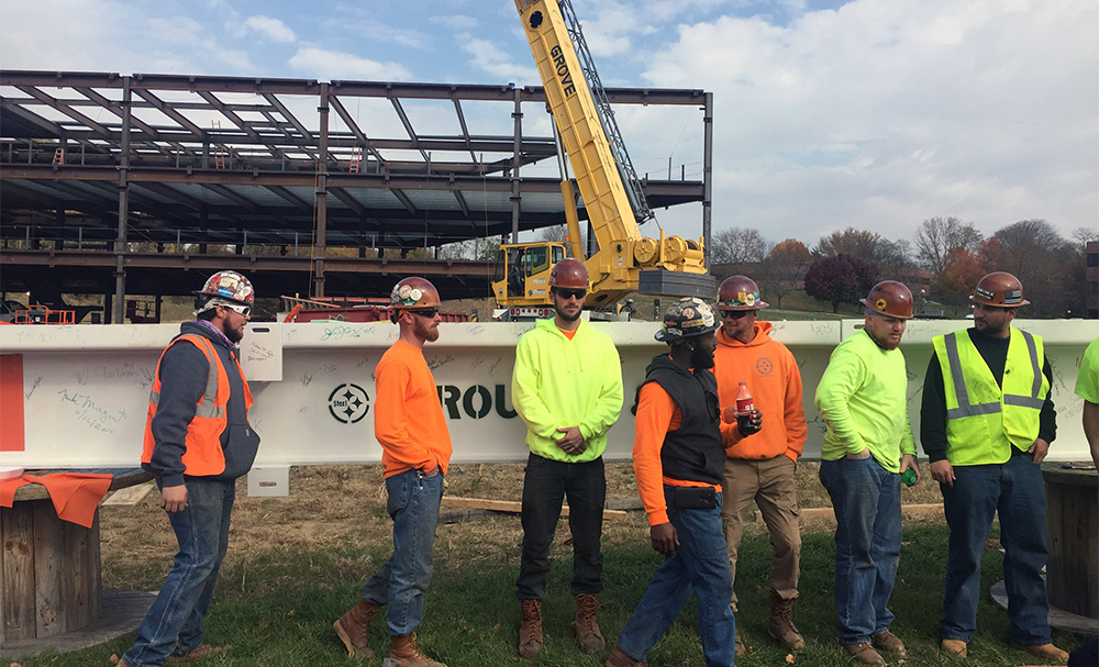 The steel workers standing in front of the final beam.