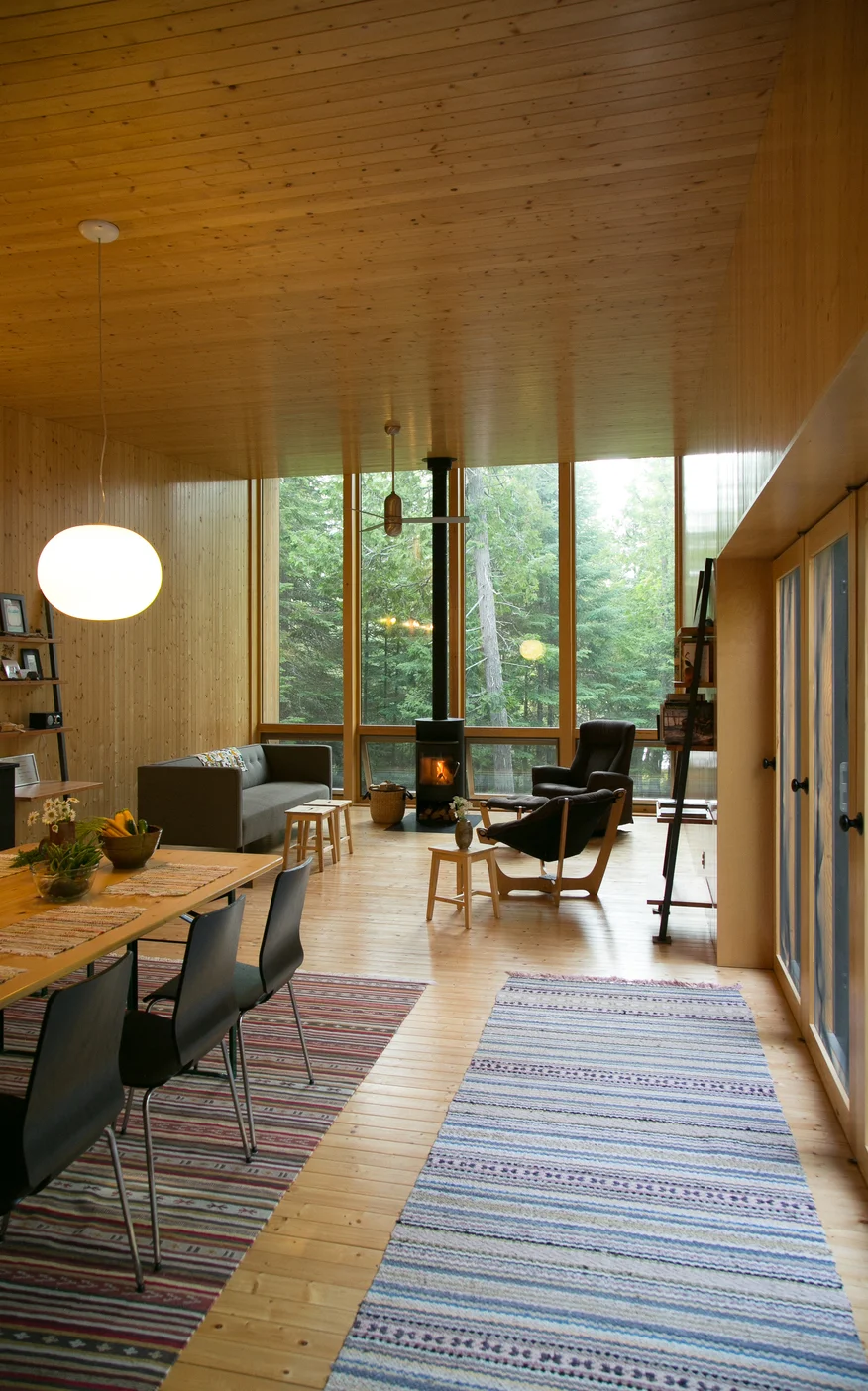 Curl up next to the modern fireplace for unbeatable lofted views of the forest and lakefront. / Source