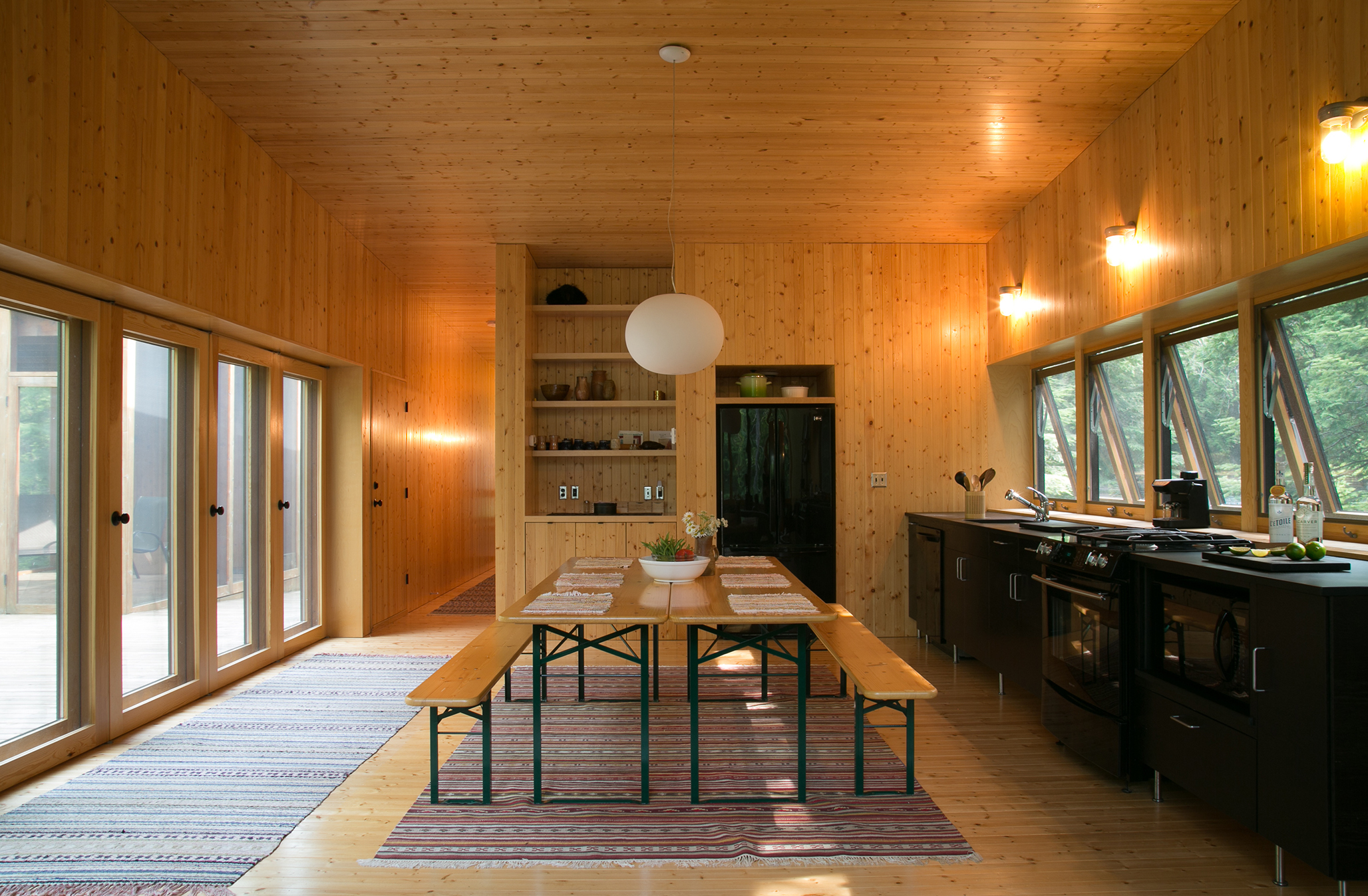 With simple wood floors and paneling, this open floor kitchen and dining space serves as the perfect spot for staycation entertainment. / Source