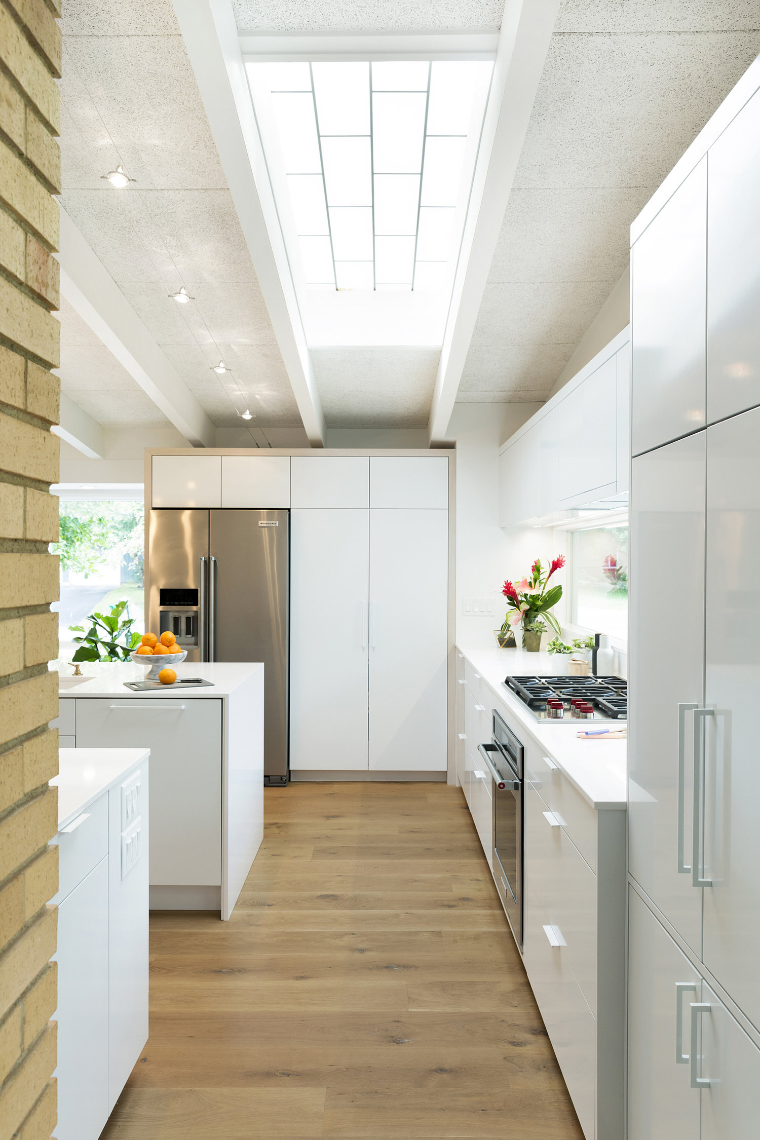 A skylight in our Midcentury Revitalization kitchen provides natural light throughout the day, creating interest via shifting shadow patterns on the floor as the sun changes its position. / Source: Vela Creative
